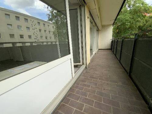 Blick von Wohnzimmer auf Balkon mit roten Bodenfliesen und Blick auf Rasen der Außenanlage.jpg - 