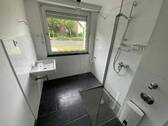 Blick in Bad mit weißen Wandfliesen, weißem Waschbecken, grauen Bodenfliesen, Hänge-WC und Dusche II.jpg - Etagenwohnung mit 77,00 m&sup2; in Meerbusch zur Miete