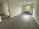 Blick in Kinderzimmer mit grauem PVC-Boden und weißen Wänden mit weißem Fenstern.jpg - 