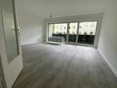 Blick in Wohnzimmer mit grauem PVC-Boden in Laminatoptik und weißen Wänden mit weißen Fenstern und weißer B.jpg - 