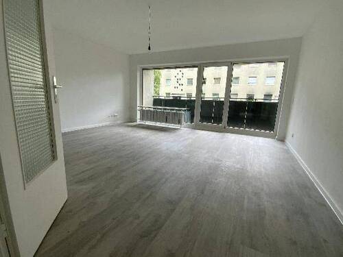 Blick in Wohnzimmer mit grauem PVC-Boden in Laminatoptik und weißen Wänden mit weißen Fenstern und weißer B.jpg - 
