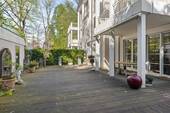 Teilüberdachte Terrasse mit Holzdielenboden und zwei separat steuerbaren Sonnenmarkisen. - 