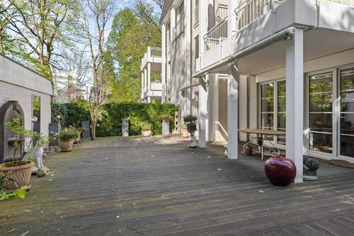 Teilüberdachte Terrasse mit Holzdielenboden und zwei separat steuerbaren Sonnenmarkisen. - 