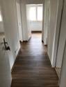 Eingangsbereich mit Zugang zu allen Zimmern der Wohnung, der Boden ist in brauner Holzoptik.jpg - 
