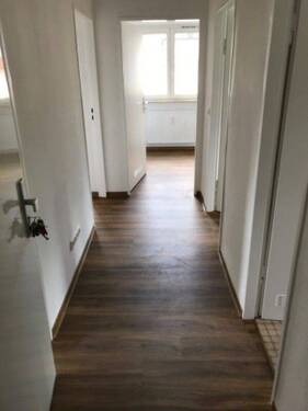 Eingangsbereich mit Zugang zu allen Zimmern der Wohnung, der Boden ist in brauner Holzoptik.jpg - 