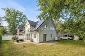 Ansicht vom Garten mit PV-Anlage und Carport - 