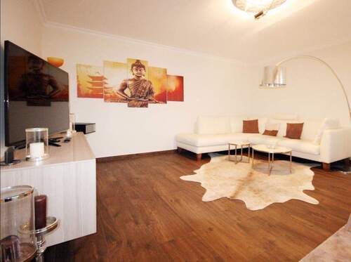 Wohnzimmer mit Couch, TV und Zugang zum Balkon - Großzügige, möblierte 2-Zi-Whg mit Südbalkon in bester Lage