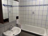 Das weiß geflieste Badezimmer verfügt über weiße Wandfliesen mit blauen Akzenten, einen Wandspiegel sowie eine Badewanne - Etagenwohnung mit 77,80 m&sup2; in Mannheim zur Miete