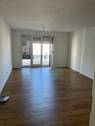 Wohnzimmer mit bodentiefen Fenstern, weißen Wänden und Boden in Holzoptik - Moderne 2-Zimmer-Wohnung mit Balkon in Wetzlar zu vermieten!