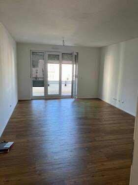 Wohnzimmer mit bodentiefen Fenstern, weißen Wänden und Boden in Holzoptik - Moderne 2-Zimmer-Wohnung mit Balkon in Wetzlar zu vermieten!