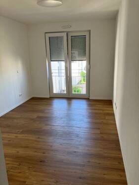 Schlafzimmer mit bodentiefen Fenstern, weißen Wänden und Boden in Holzoptik - 2 Zimmer Etagenwohnung in Wetzlar