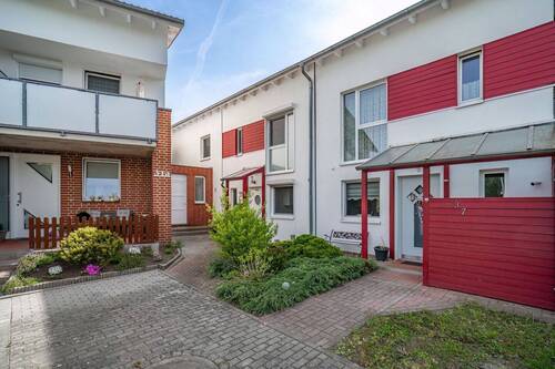 Die weiße Fassade mit roten Holzelementen verleiht dem Haus einen modernen Charakter. - 