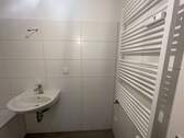 Badezimmer mit Waschbecken und Handtuchheizkörper, weiß gefliest - 