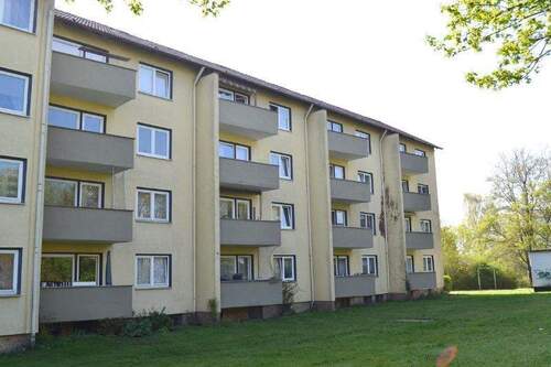 Akazienallee 42 + 44, Außenansicht über die Grünanlage mit altem Baumbestand mit Blick auf die Westbalkone eines mehrgeschossigen Wohngebäudes. - Ideal für Zwei: Kleine 3-Zimmerwohnung am Baunsberg