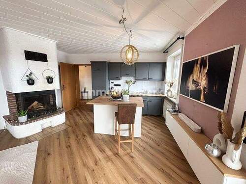 Wohnzimmer mit Kamin und offener Küche - 