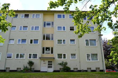  Vorderansicht eines mehrstöckigen Wohngebäudes , umgeben von Bäumen und grünen Sträuchern - Schicke 4-Zimmer-Wohnung - 620,00&nbsp;EUR Kaltmiete, ca.&nbsp; 73,40&nbsp;m&sup2;&nbsp;Wohnfl&auml;che