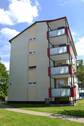  Rückansicht eines mehrstöckigen Wohngebäudes mit Balkonen, umgeben von Bäumen und grünen Sträuchern - 4 Zimmer Etagenwohnung in Kassel