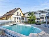 Einladende Poolanlage, eingerahmt von Altbau (gelb) und Neubau (grau) - Zwei Häuser - ein Zuhause: Ihr Mehrgenerationen-Traum