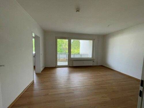 Wohnzimmer mit weißen, tapetenlosen Wänden, Deisgn-Vinylboden in Holzoptik und Zugang zum Balkon, sowie zum Schlafzimmer. - 1 Zimmer Etagenwohnung zur Miete in Bad Homburg vor der Höhe