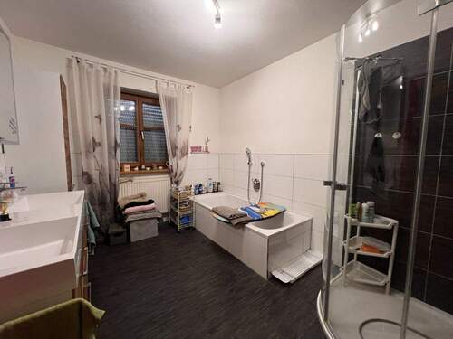 Geräumiges Badezimmer mit Badewanne, Dusche und praktischer Stauraumlösung - 