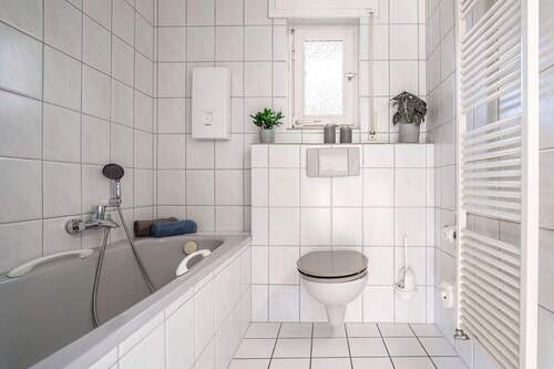 Weiße Fliesen in Kombination mit hellgrauer Keramik schaffen ein harmonisches Gesamtbild. - 