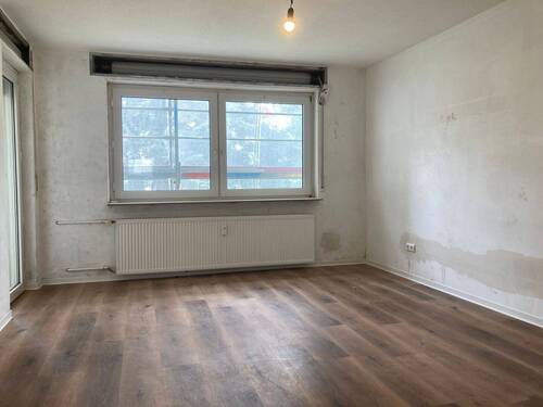 Wohnzimmer mit neuem Fußbodenbelag in Holzoptik, die Wände sind tapezierfertig vorbereitet - 