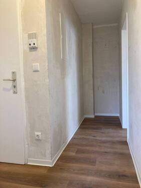 Flur mit neuem Bodenbelag in Holzoptik, die Wände sind tapezierfertig vorbereitet - 