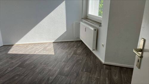 Ansicht Schlafzimmer mit hellen Wänden und grauem Boden in Holzoptik - 