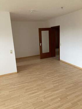 mit Laminat ausgelegtes Wohnzimmer, Blick zur Holztür mit Glaseinsatz, links eine Trennwand.JPG - 