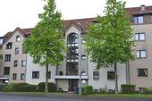 Theodor-Heuss-Allee 19, Außenansicht auf den Eingangsbereich eines mehrgeschossigen Wohngebäudes in Reihenbebauung (Mittelhaus) und heller Fassade - Ganz oben: Dachgeschosswohnung in zentraler Lage von Altenbauna
