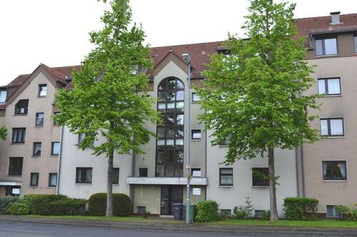 Theodor-Heuss-Allee 19, Außenansicht auf den Eingangsbereich eines mehrgeschossigen Wohngebäudes in Reihenbebauung (Mittelhaus) und heller Fassade - Ganz oben: Dachgeschosswohnung in zentraler Lage von Altenbauna
