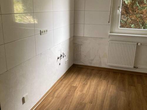 Küche mit Fenster mit tapezierfähigen Wänden und hellem Fliesenspiegel. Es ist ein PVC-Boden in Holzoptik verlegt. - 