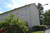 Seitenansicht eines mehrstöckigen Wohngebäudes , umgeben von Bäumen und grünen Sträuchern - 3 Zimmer Etagenwohnung zur Miete in Kassel