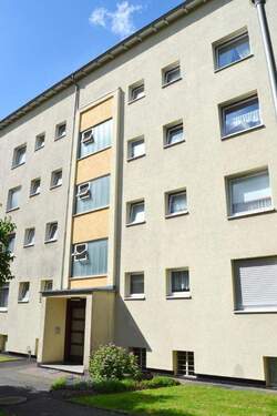 Vorderansicht eines mehrstöckigen Wohngebäudes umgeben von Bäumen und grünen Sträuchern - 3 Zimmer Etagenwohnung zur Miete in Kassel