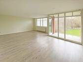 Wohnzimmer mit großer Glasfront und Tür zum Balkon - Etagenwohnung mit 87,60 m² in Stade zum Kaufen