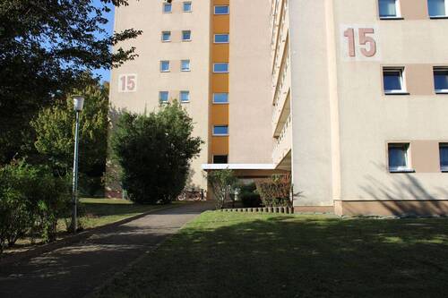 Vorderansicht des Gebäudes mit Eingangsbereich und Grünanlage - 3-Zimmer-Wohnung kurzfristig verfügbar