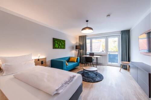 Schlafzimmer 1 mit Balkon, Arbeitsbereich, Bett, Couch und TV - Top möblierte Design-Wohnung mit zwei Schlafzimmern inklusive Arbeitsplatz + Balkon nahe der Isar