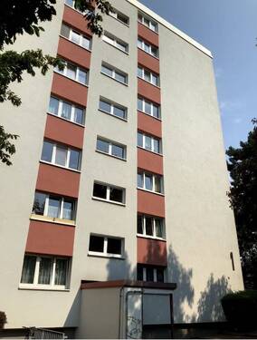 Außenansicht eines mehrstöckigen Wohnhauses, umgeben von Bäumen. - Schöne 4-Zimmer-Wohnung mit Balkon zu vermieten!