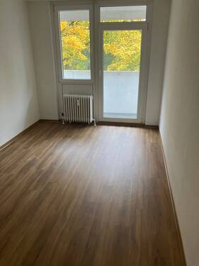 Schlafzimmer mit Design-Vinylboden in Holzoptik, weißen Wänden, sowie Zugang zum Balkon. - 4 Zimmer Etagenwohnung in Frankfurt am Main