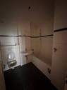 Badezimmer mit weißen Wand- und dunklen Bodenfliesen, weißem Waschbecken, WC und Badewanne. - Etagenwohnung mit 93,90 m&sup2; in Frankfurt am Main zur Miete