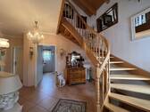 Elegante Eingangshalle mit geschwungener Holztreppe und offener Raumstruktur - 