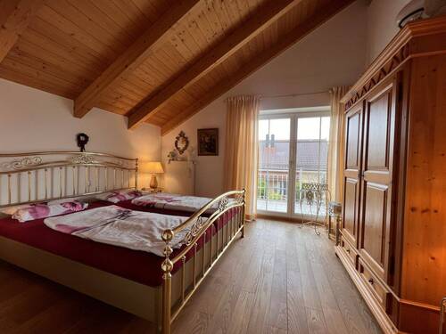 Komfortables Hauptschlafzimmer mit Holzbalkendecke und Balkonzugang - 