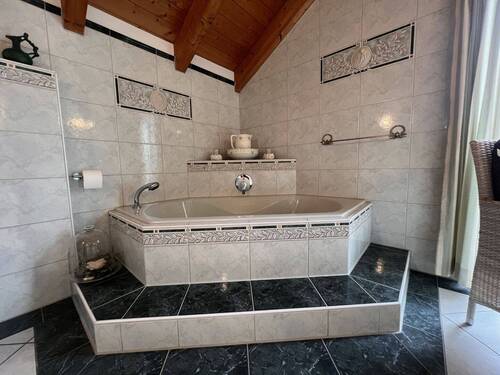 Wellness-Badezimmer mit Eckwanne, Regendusche und Holzbalkendecke - 