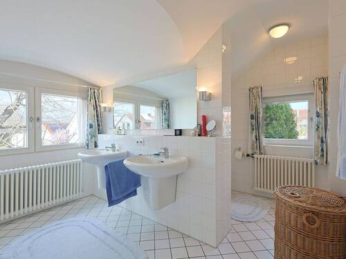 Hell gefliestes Tageslichtbadezimmer mit Doppelwaschbecken, WC-Nische, Badewanne und Dusche - 