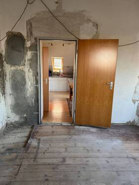 Wohnung 1.OG links Blick vom unsanierten Nordzimmer in die Küche - 