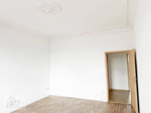 Wohnzimmer mit Stuckdecke und Blick Richtung Flurbereich - Etagenwohnung mit 74,10 m&sup2; in Riesa zur Miete