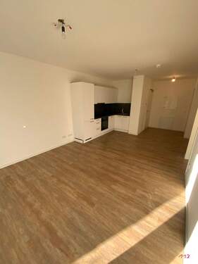 Wohn-Essbereich mit weißen Wänden und holzfarbenen Vinylboden - 2 Zimmer Etagenwohnung zur Miete in Frankfurt am Main