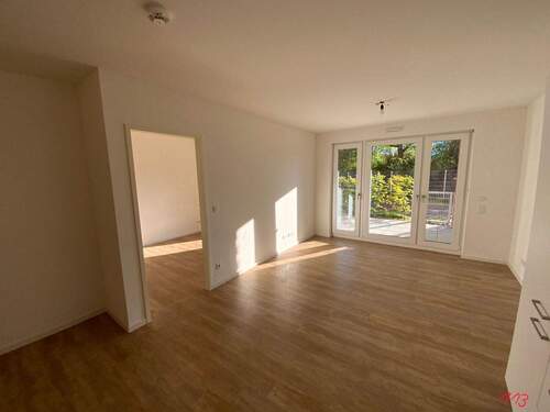 Wohnzimmer mit weißen Wänden und holzfarbenen Vinylboden - 2 Zimmer Etagenwohnung in Frankfurt am Main