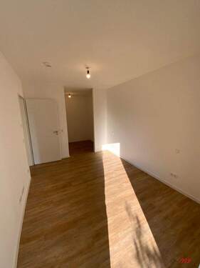 Schlafzimmer mit weißen Wänden und holzfarbenen Vinylboden - 