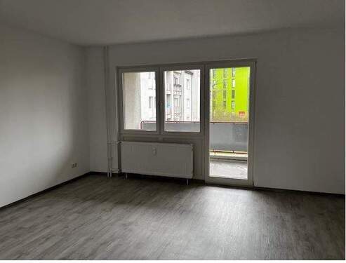 Wohnzimmer mit Zugang zum Balkon. Helle Wände und hellgrauer Bodenbelag in Holzoptik.JPG - Etagenwohnung mit 79,00 m&sup2; in Baunatal zur Miete